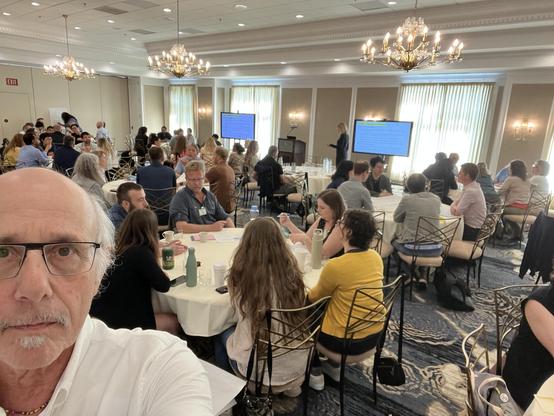 selfie in a room full of people at round tables