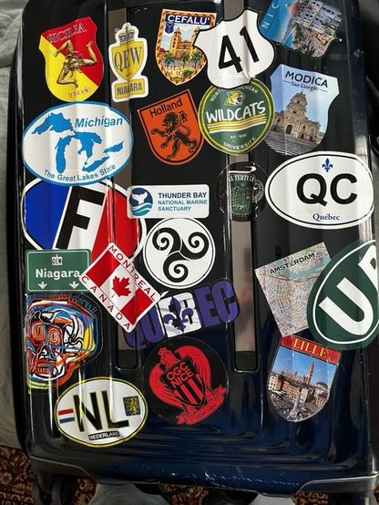 The Collection:
This is clearly the suitcase of a serious traveler who enjoys documenting their journeys. The heavy concentration of Michigan stickers alongside extensive European destinations (particularly Netherlands, France, and Italy/Sicily) tells the story of someone rooted in Michigan but with deep European travel experience. The mix of official destination ovals, tourist attraction stickers, and local city emblems creates a visual travel diary covering both sides of the Atlantic.

ALT by…