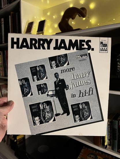 This photo shows a classic jazz reissue album featuring the legendary trumpeter Harry James.

The Album:
"More Harry James in Hi-Fi"

Released on Pausa Records (Jazz Origin Series)

Catalog number PR 9037

Album Design:
Bold black text "HARRY JAMES." across the top

Meta-design showing multiple copies of Harry James album covers arranged in a grid

Central photograph of Harry James in a sharp suit holding his trumpet

Black and white photography

Text reads "more harry james in hi-fi" in styliz…
