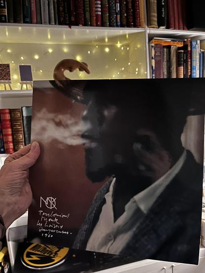 This photo shows a historic jazz album with dramatic black and white photography and handwritten notes.

The Album:
Thelonious Monk album

Subtitle: "les liaisons dangereuses - 1960" (Dangerous Liaisons)

The Monk logo (stylized "M" with musical note) visible in white

Album Design:
Striking black and white photography

Moody, atmospheric close-up of Monk

Dark tones with dramatic lighting creating deep shadows

Monk appears to be smoking, captured in profile/three-quarter view

Artistic, cinem…