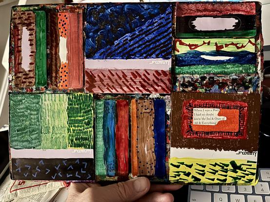 Three J-cards (the larger, full-size paper inserts that wrap around a cassette case) and six labels (the smaller pieces that go directly on the cassette shell, some with the die-cut window for the tape reels), all hand-painted are arranged into a grid on a heavily paint-spattered cardboard palette, held up in one hand over a desk with a keyboard below.

The FYDELITY branding is visible peeking through on a few of the labels, and the whole palette is unified by the drips and test-strokes built u…
